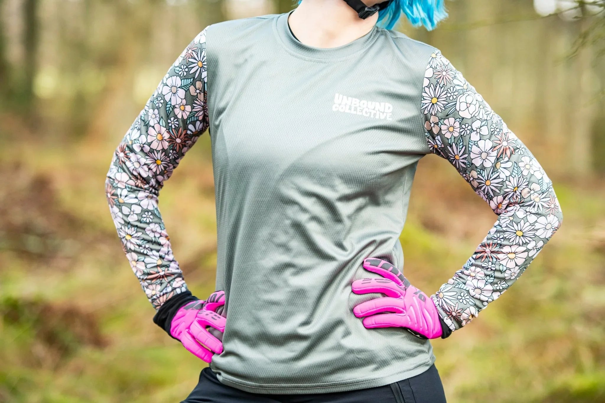 Woman in retro floral long-sleeve mountain bike jersey with pink gloves in forest setting
