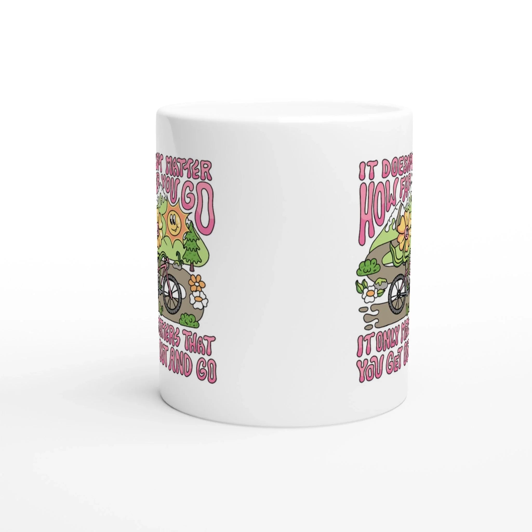 White ceramic mug with colorful mountain bike illustration and inspirational quote in pink text