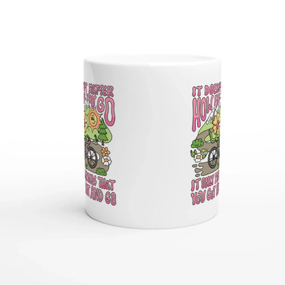 White ceramic mug with colorful mountain bike illustration and inspirational quote in pink text